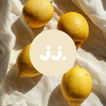 Citron jaune sur tissu clair avec logo jj., évoquant la senteur Citronnelle & Citron. 