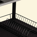 Panier de rangement en métal noir installé sur l’étagère inférieure d’un module de cuisine extérieure, présenté en gros plan sur fond clair.