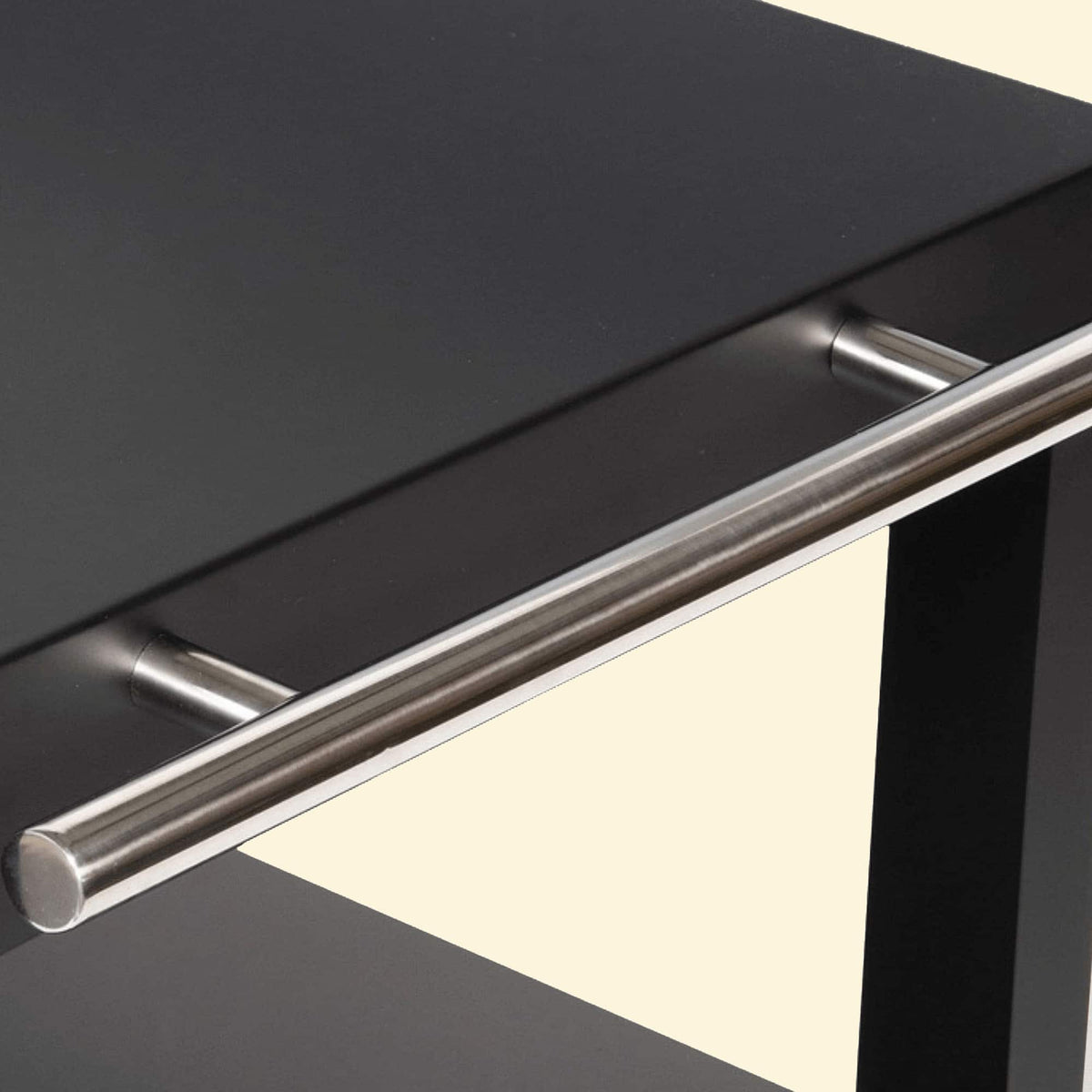 Gros plan sur la barre de poignée en inox d’une desserte de plancha noire, fixée sur le côté du plateau supérieur.