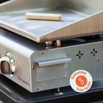 Close-up van de Vivaplancha plancha met de roestvrijstalen vetopvangbak en een reinigingsgereedschap op de plaat, met een badge “Zeer eenvoudig onderhoud”.