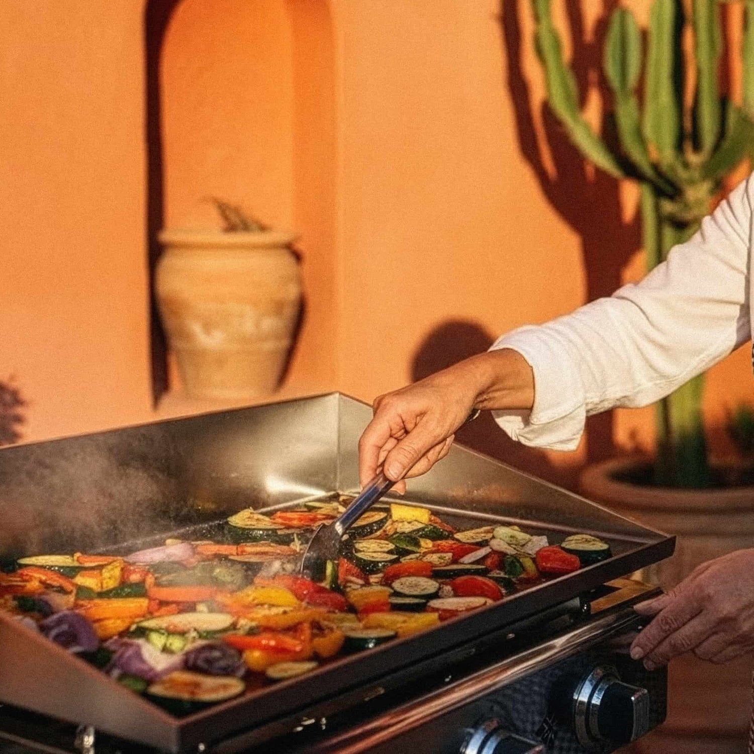 Chef cuisinant des légumes et viandes sur une plancha inox vivaplancha, maîtrise de la cuisson à haute température